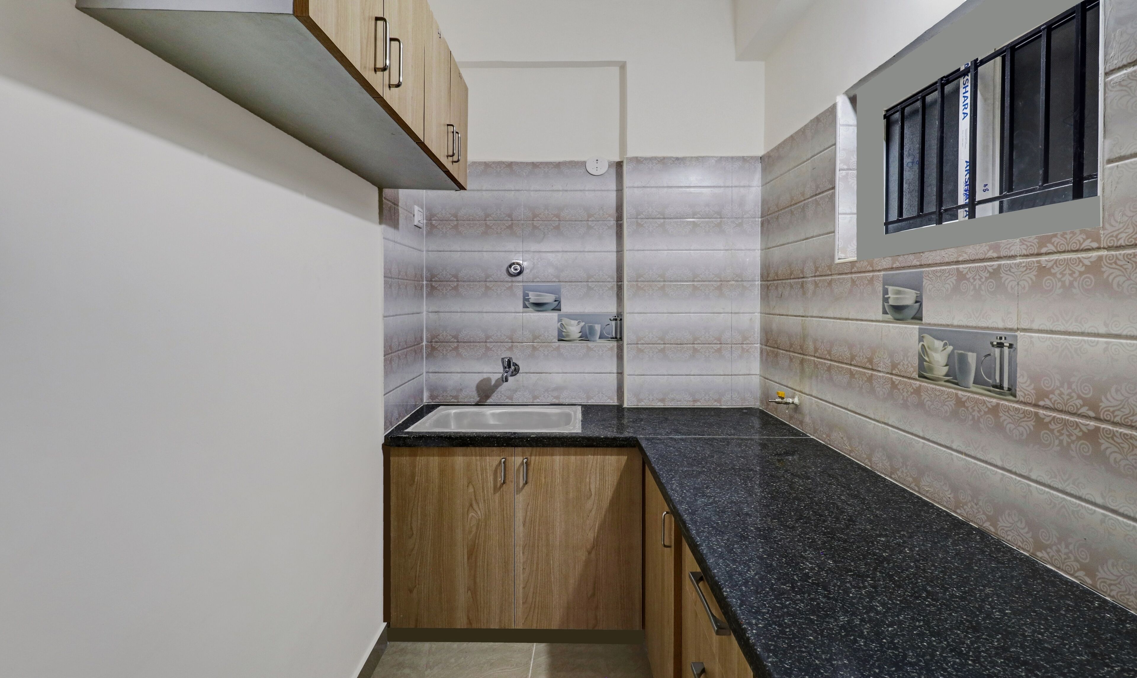 Une cuisine avec des meubles en bois, un plan de travail en granit et des carreaux décoratifs sur le mur derrière l’évier.