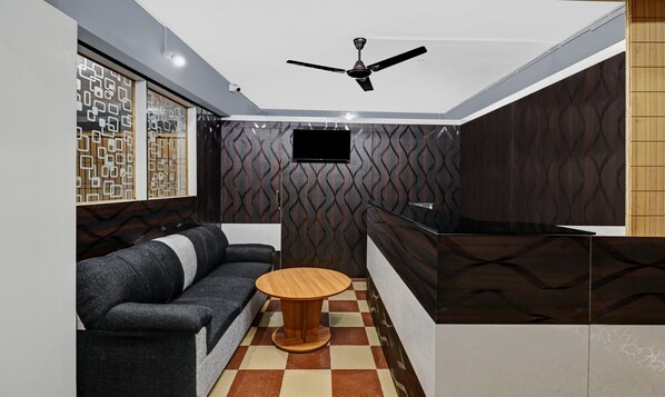 A modern interior with a sofa, a round wooden table, a ceiling fan, and a TV mounted on the wall.