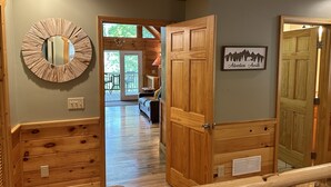 A wooden interior hallway with a mirror, a door leading to a balcony, and a framed picture on the wall. - River Shoals Cabin! Hot Tub-Water front (Cleveland)