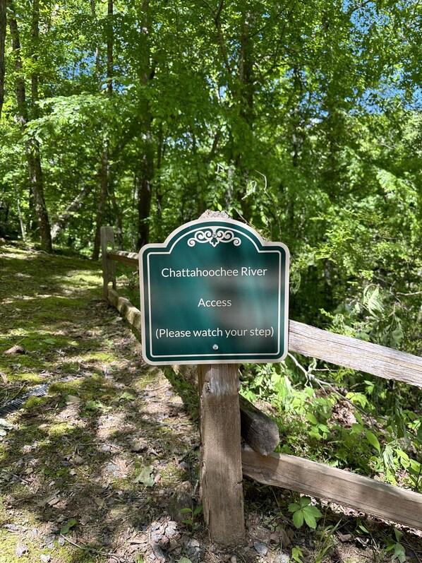 A sign in a forested area with the text "Chattanooga River Access (Please watch your step)".