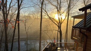 A wooden deck overlooking a body of water with trees in the background and a clear sky. - River Shoals Cabin! Hot Tub-Water front (Cleveland)