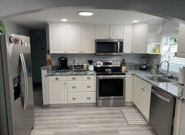 A modern kitchen with white cabinets, stainless steel appliances, and a microwave.