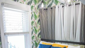 Un dormitorio con cama, cortinas y ventana con persianas.