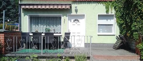 Un edificio pequeño con fachada verde, una puerta blanca y una ventana pequeña.
