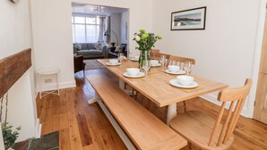 Un coin repas avec une table en bois dressée pour quatre personnes, des bancs et un vase rempli de fleurs.