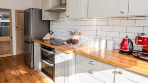 Une cuisine moderne dotée d’appareils électroménagers en acier inoxydable, de meubles blancs et d’un plan de travail en bois.