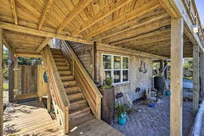 Une cabane en bois avec un escalier en bois menant à une terrasse, une fenêtre et une plante en pot.