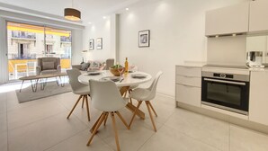 Uma cozinha moderna com armários brancos, forno embutido e área de refeições com mesa e cadeiras redondas.
