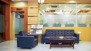 A lobby with a dark blue sofa, a smaller armchair, and a wooden coffee table. There is a sign above the door labeled "Pavilion." - Comfort Inn Udaipur (Udaipur)
