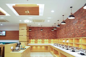A modern restaurant with a brick wall, wooden counter, and pendant lighting.