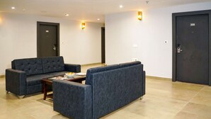 A modern lobby with dark-colored sofas, a coffee table, and two doors labeled 306 and 308. - Comfort Inn Udaipur (Udaipur)
