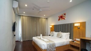 A hotel room with a large bed, a wooden headboard, a bedside table with a lamp, and a wall-mounted TV. - Comfort Inn Udaipur (Udaipur)