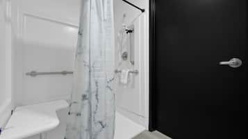 Un baño con un lavamanos blanco, una ducha con cortina de mármol y una puerta negra.