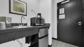 Una cocina moderna con un refrigerador de acero inoxidable, un microondas y un lavamanos.