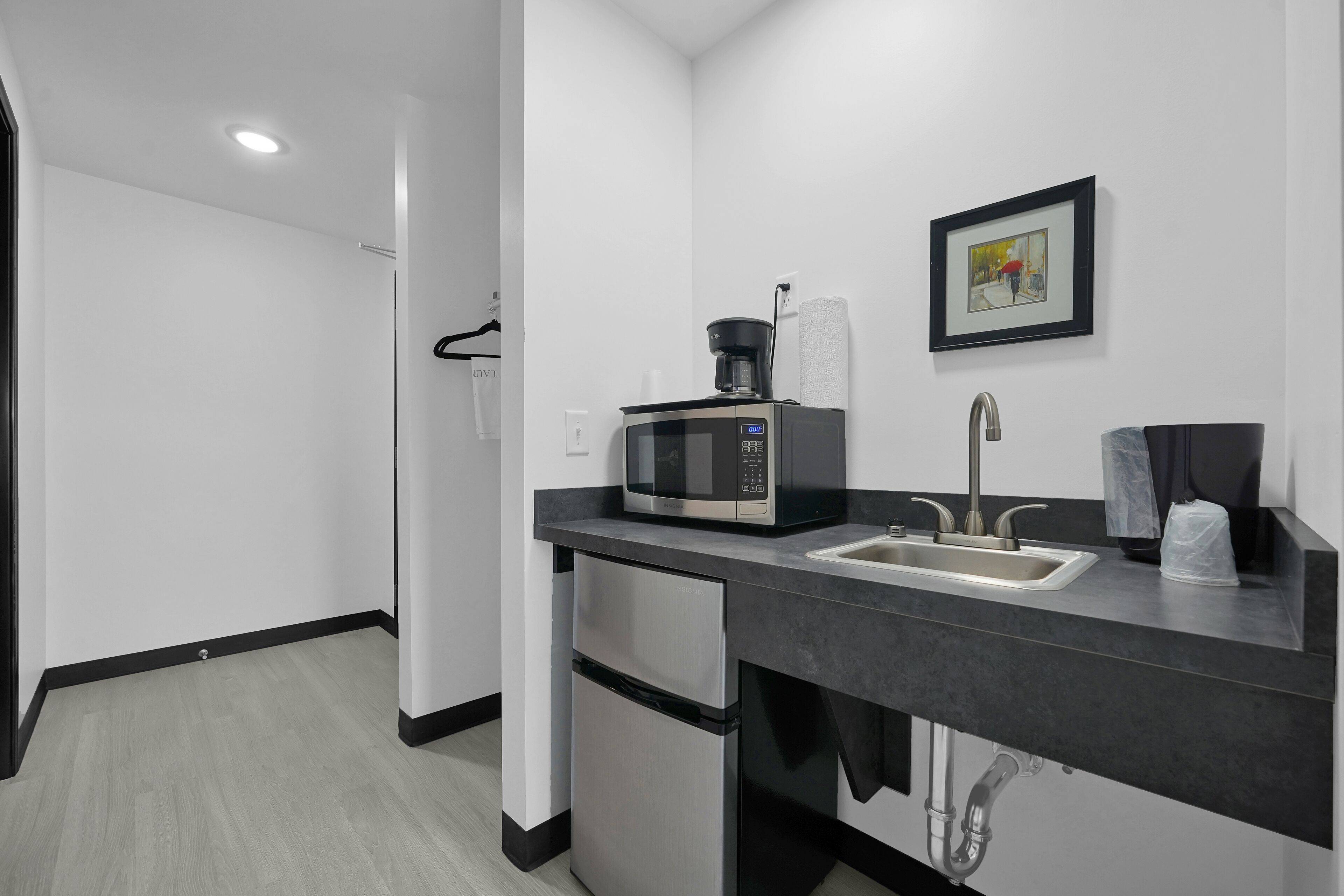 A compact kitchen with a microwave, sink, and small refrigerator.