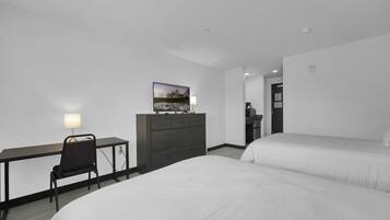 Habitación de hotel con escritorio, silla, dos camas, cómoda y un cuadro en la pared.