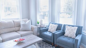 Un salon comprenant un canapé, deux fauteuils, une table basse et une lampe.
