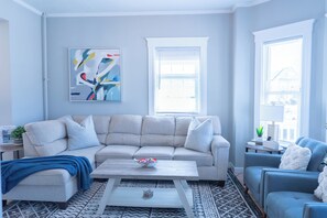 Uma sala de estar com sofá, mesa de centro e um quadro na parede.