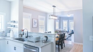 Une cuisine moderne dotée d’un îlot central, d’appareils électroménagers intégrés et d’un coin repas avec une table et des chaises.