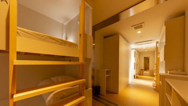 Ein Hotelzimmer mit einem Etagenbett, einem kleinen Schreibtisch und einem Spiegel.