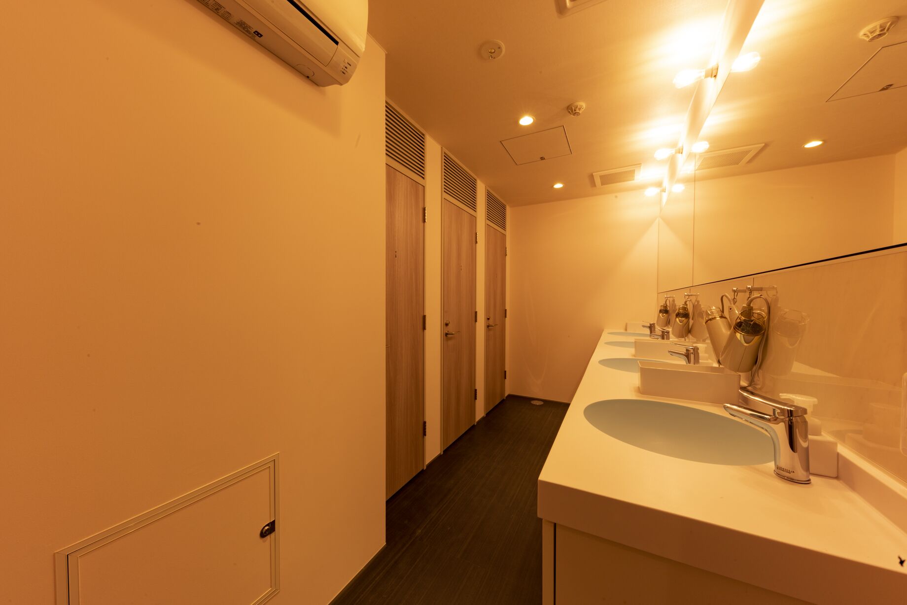 A hotel bathroom with a long counter, multiple sinks, and a large mirror.