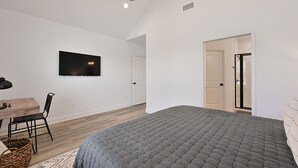 A bedroom with a bed, a TV mounted on the wall, a dining table with chairs, and a ceiling fan. - Newly built home minutes from Texas A&M campus (College Station)