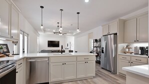 A modern kitchen with white cabinetry, stainless steel appliances, and pendant lighting. - Newly built home minutes from Texas A&M campus (College Station)