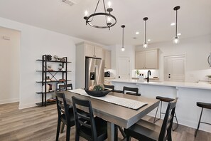 Una cocina moderna con armarios blancos, una isla central e iluminación colgante.