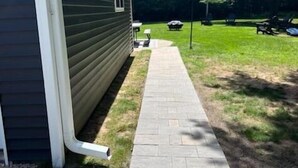 En stig som leder fram till ett hus med mörk fasadbeklädnad.