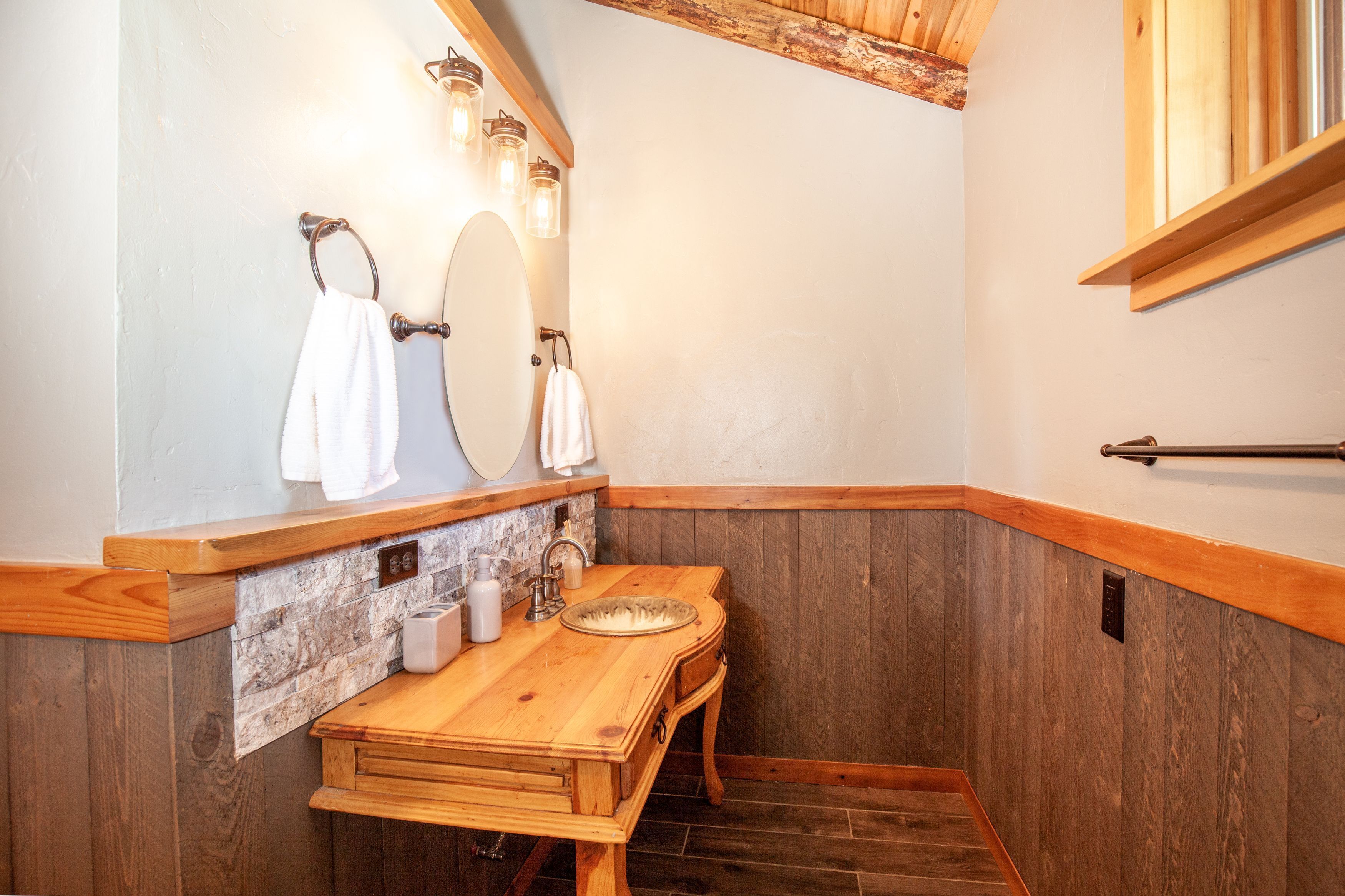 Une coiffeuse en bois avec un miroir, un lavabo et un porte-serviettes.