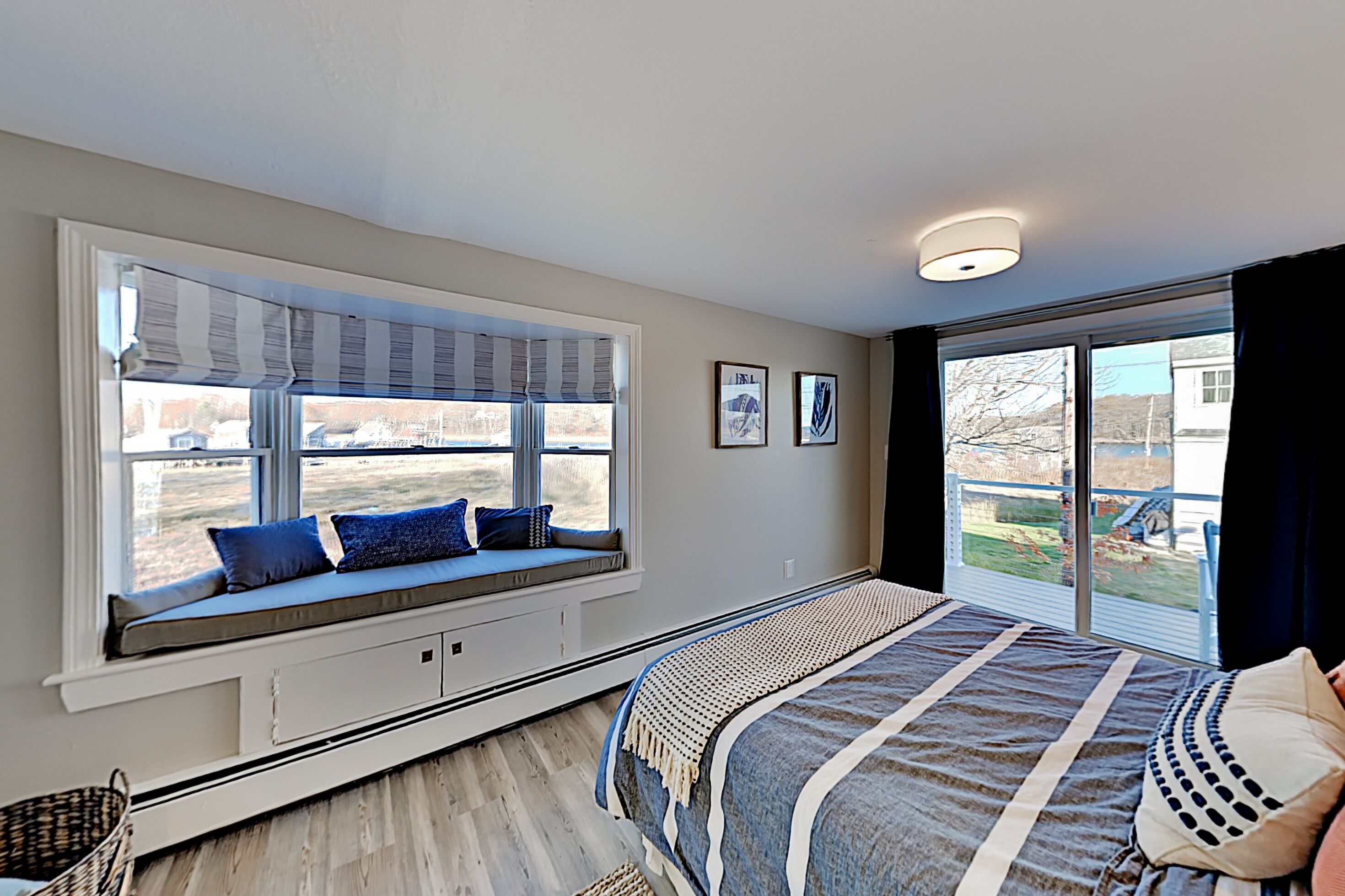 Une chambre avec un grand siège de fenêtre, un lit recouvert d’une courtepointe à rayures et une vue sur l’extérieur.