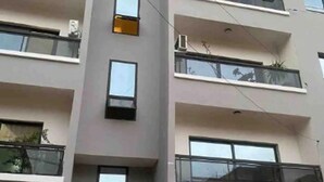A multi-story residential building with balconies, air conditioning units, and a person in a red shirt. - Chambre privé en résidence sécurisée (Dakar)