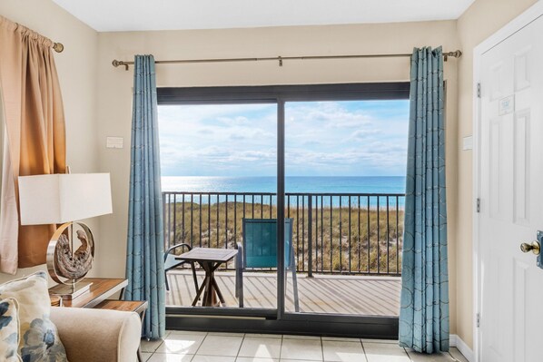 A balcony with a view of the sea, a table, and a chair.