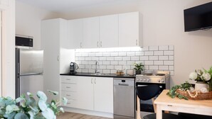 Une cuisine moderne avec des meubles blancs, un réfrigérateur en acier inoxydable, un lave-vaisselle et une cuisinière.