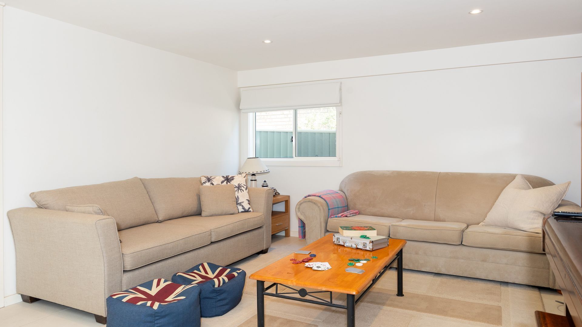 A living room with two beige sofas, a wooden coffee table, and blue cushions with a Union Jack pattern.