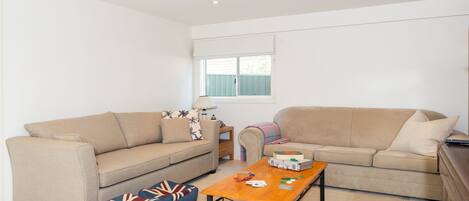 A living room with two beige sofas, a wooden coffee table, and blue cushions with a Union Jack pattern.