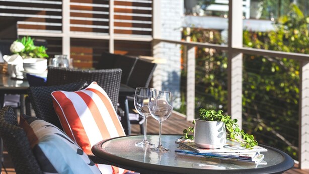 A round table with two wine glasses, a small potted plant, and a few books.