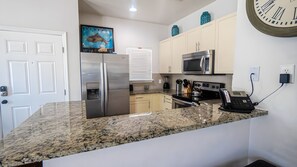 A modern kitchen with granite countertops, stainless steel appliances, and a water dispenser.