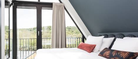 Een slaapkamer met een groot bed, uitzicht op groen en een modern plafondontwerp.
