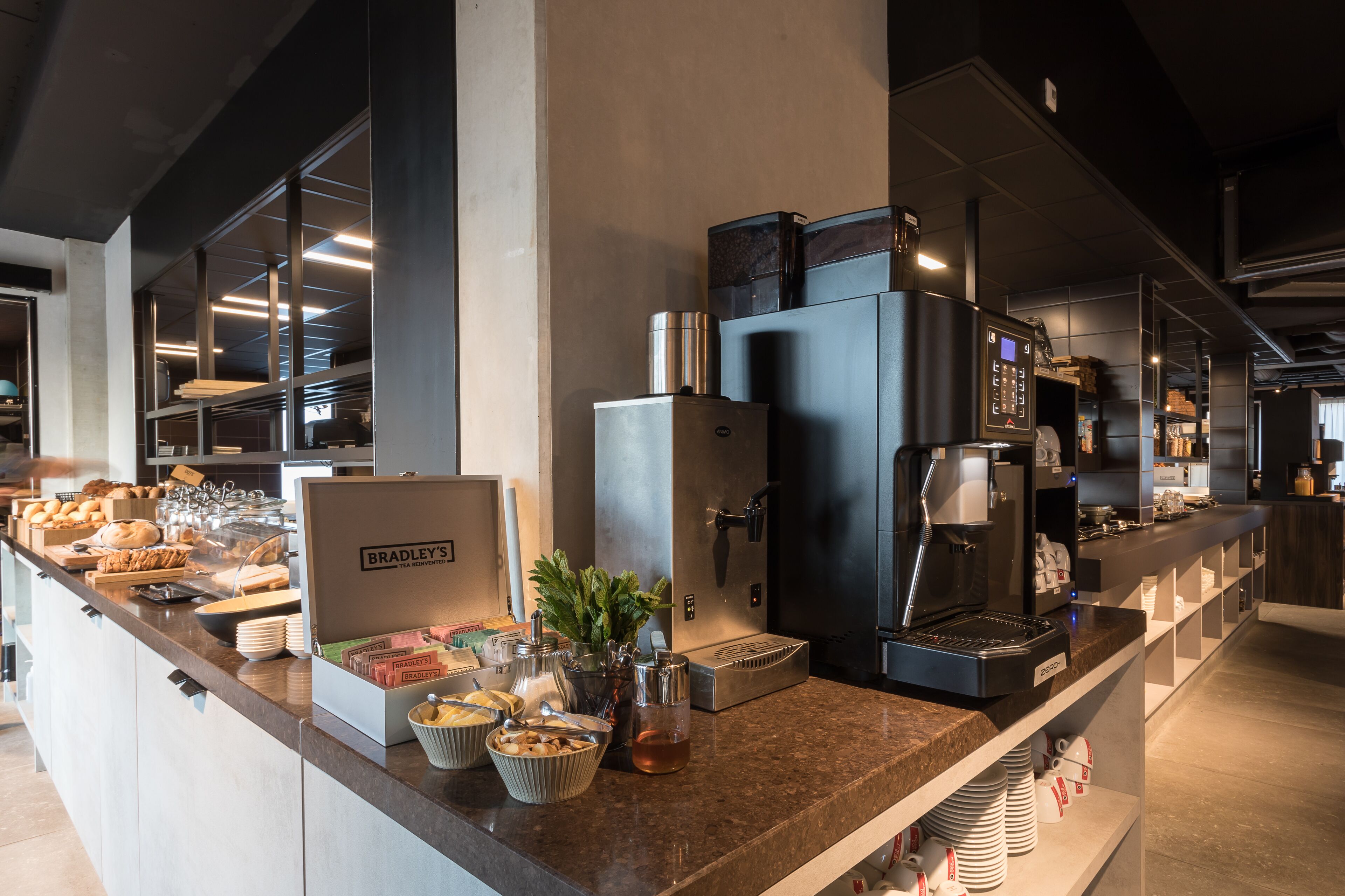 Een ontbijtbuffet met diverse soorten eten, een koffieapparaat en een theeservies.