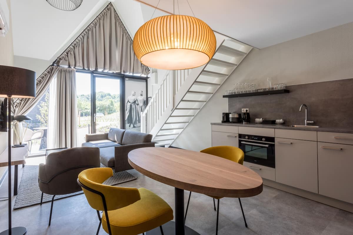 Una cucina moderna con zona pranzo, che presenta un tavolo in legno, sedie gialle e una grande lampada a sospensione.