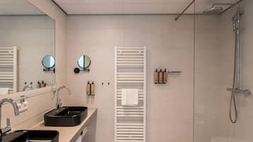Un baño moderno con dos lavamanos, un espejo, un perchero para toallas y una zona de ducha.