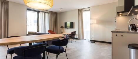 Ein modernes Hotelzimmer mit Essbereich, einer Küche und einem großen Fenster.