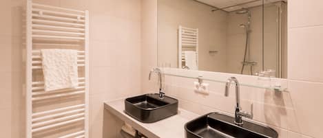 Un baño moderno con dos lavamanos, un estante de vidrio y un espejo grande.