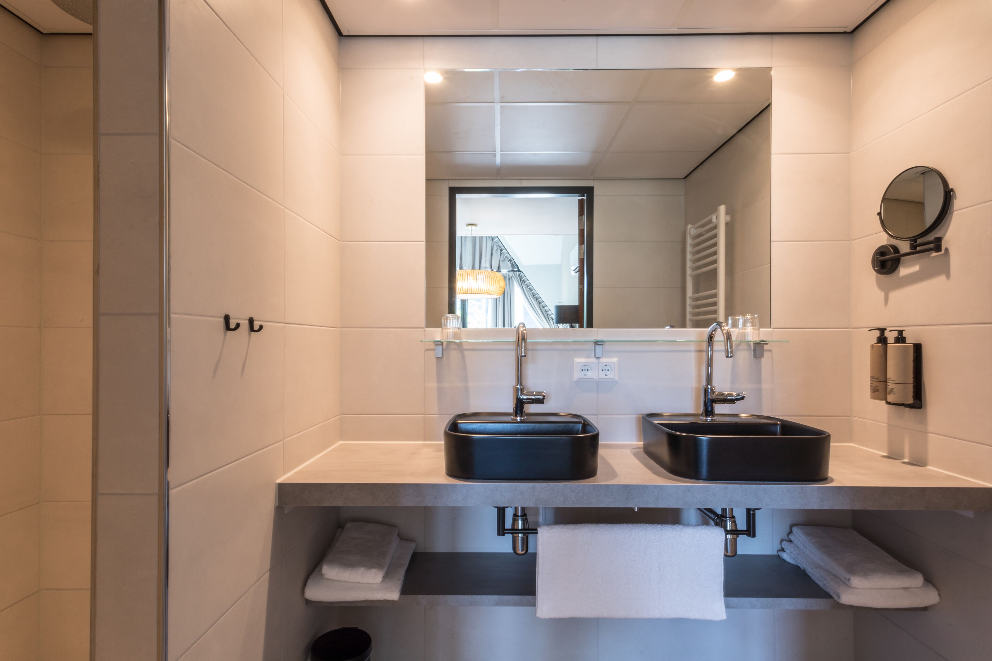 Ein modernes Badezimmer mit zwei Waschbecken, einem Spiegel und einem Handtuchhalter.