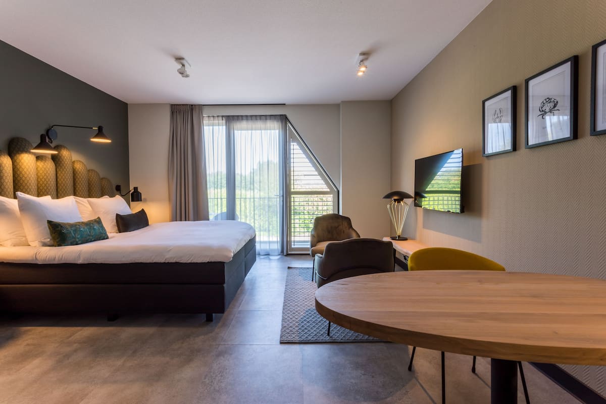 Camera d'albergo moderna con un letto grande, un tavolo da pranzo e vista sull'esterno.