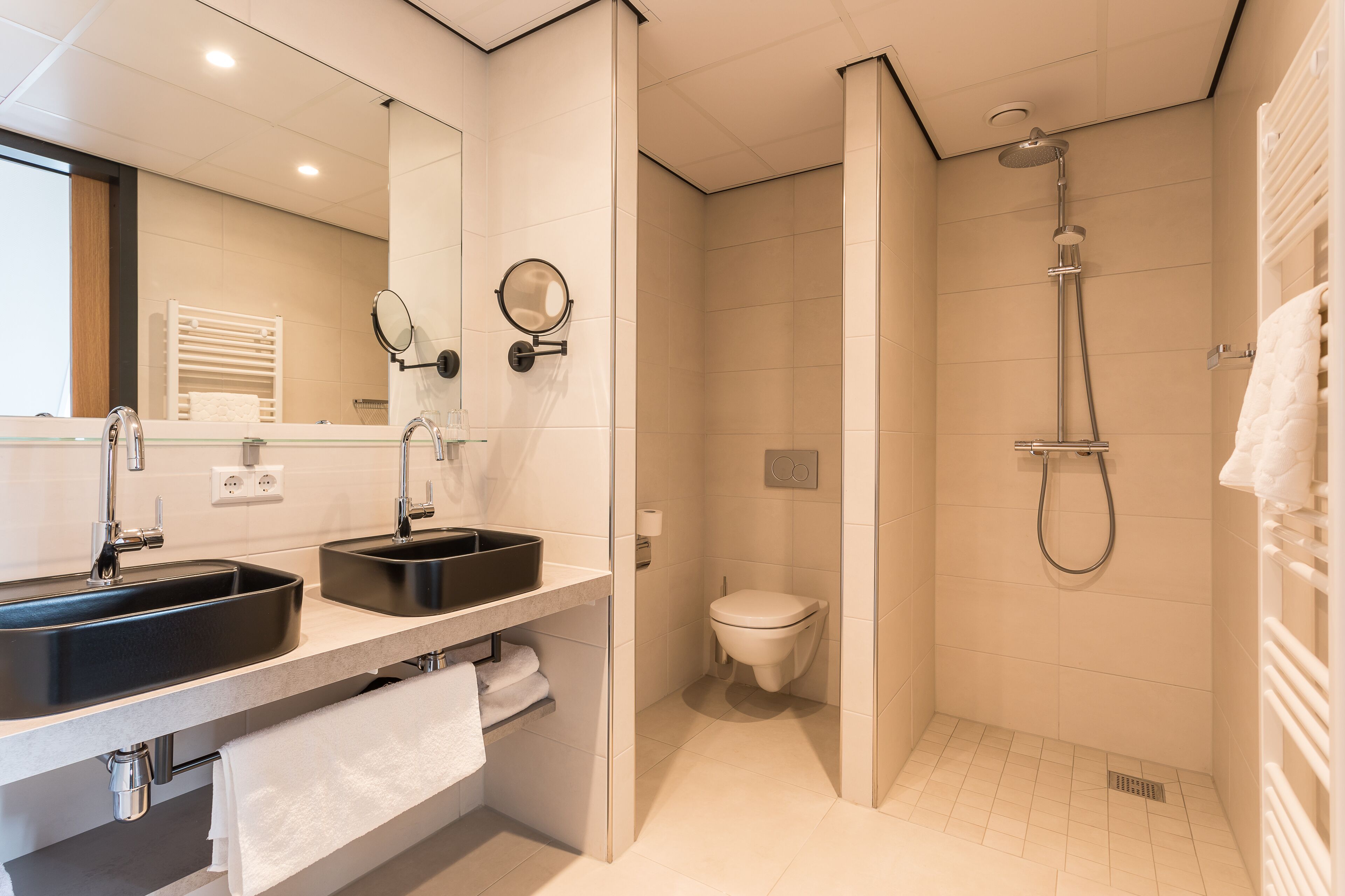 Une salle de bain moderne avec un double vasque, des toilettes et une douche.