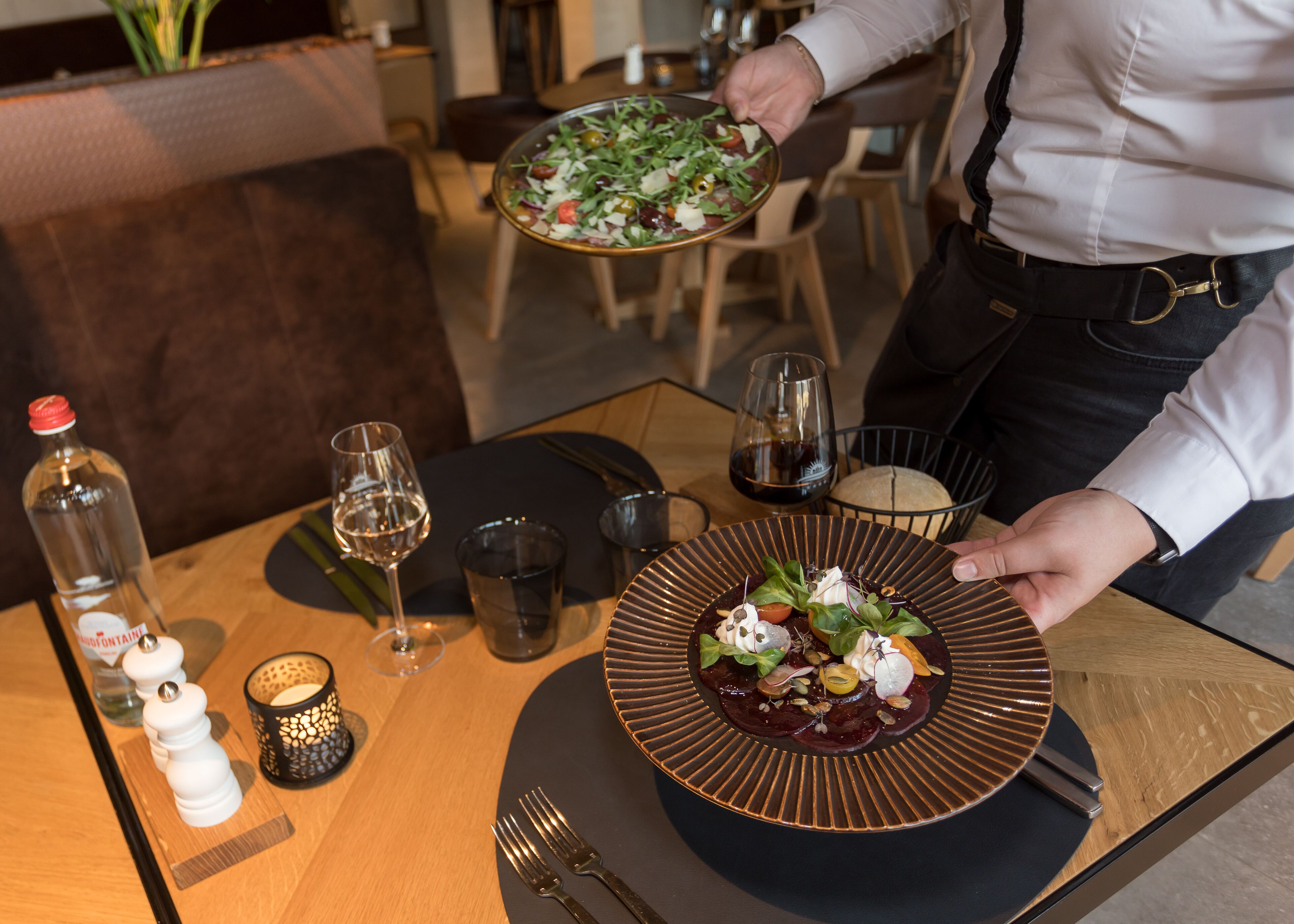 Una mesa de comedor con un plato de comida, copas de vino y cubiertos.