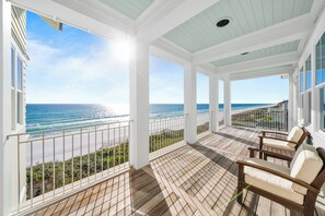 A covered balcony with a view of the ocean, wooden flooring, and two cushioned chairs. - 30A Stunner! Gulf Views, Private Pool, Beach & Golf Cart | Fall Now Booking! (Santa Rosa Beach)
