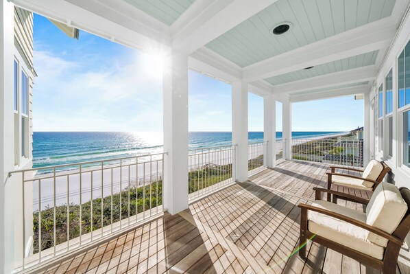 A covered balcony with a view of the ocean, wooden flooring, and two cushioned chairs. - 30A Stunner! Gulf Views, Private Pool, Beach & Golf Cart | Fall Now Booking! (Santa Rosa Beach)